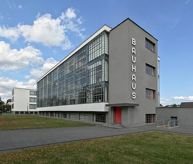 Photograph of the Bauhaus building in Dessau, viewed from the south-east, showing the workshop wing and the glass curtain wall facade